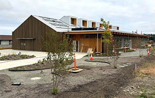 Looking at the southwest exterior towards the main entrance. Picnic tables will be added to the two concrete pads along the gravel path.