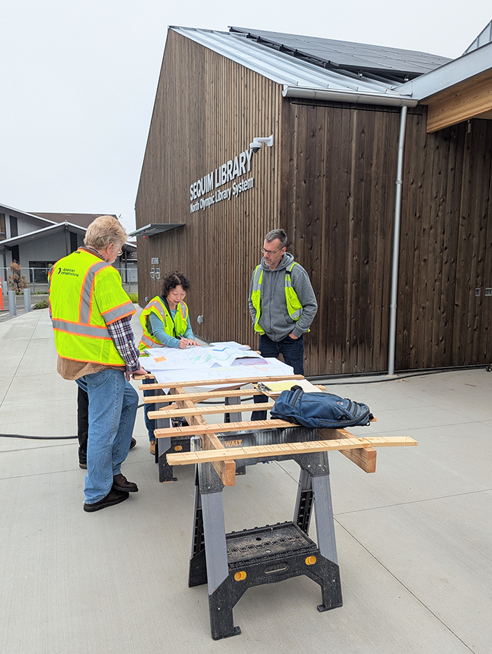 Mari Hamasaki (center) of Hamasaki Consulting Engineering Services reviews plans to ensure mechanical systems work as designed during the Sequim Library commissioning process with NOLS Facilities Technician Eric Tapp (left) and NOLS Facilities Manager Brian Phillips (right).