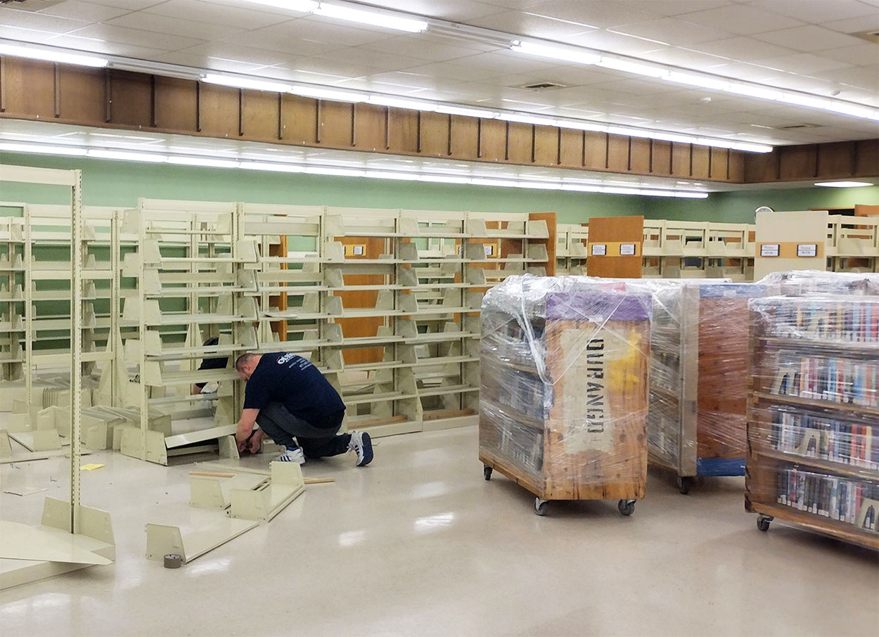 Professional movers deinstalled shelves and wrapped book carts.