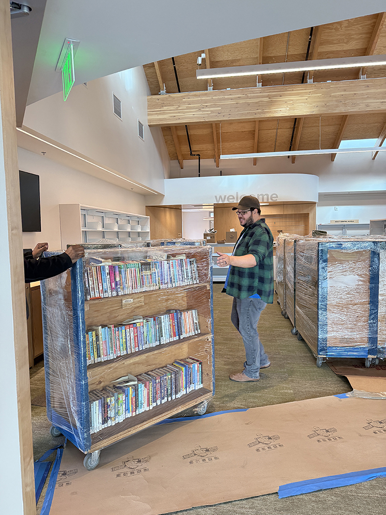 Moving carts are organized in front of the welcome desk for staff to begin shelving.